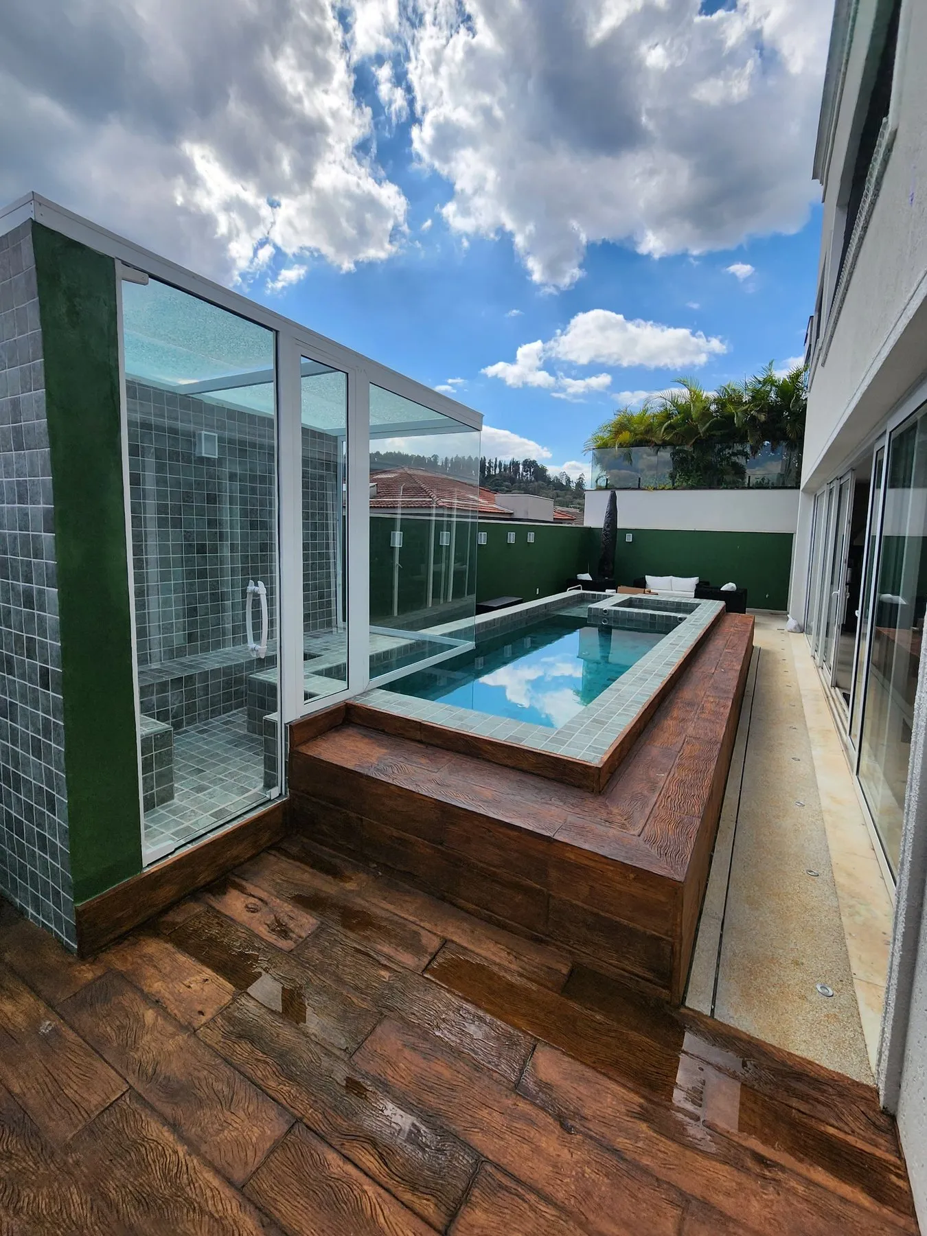 Deck de madeira ao lado da piscina e box de vidro ao fundo