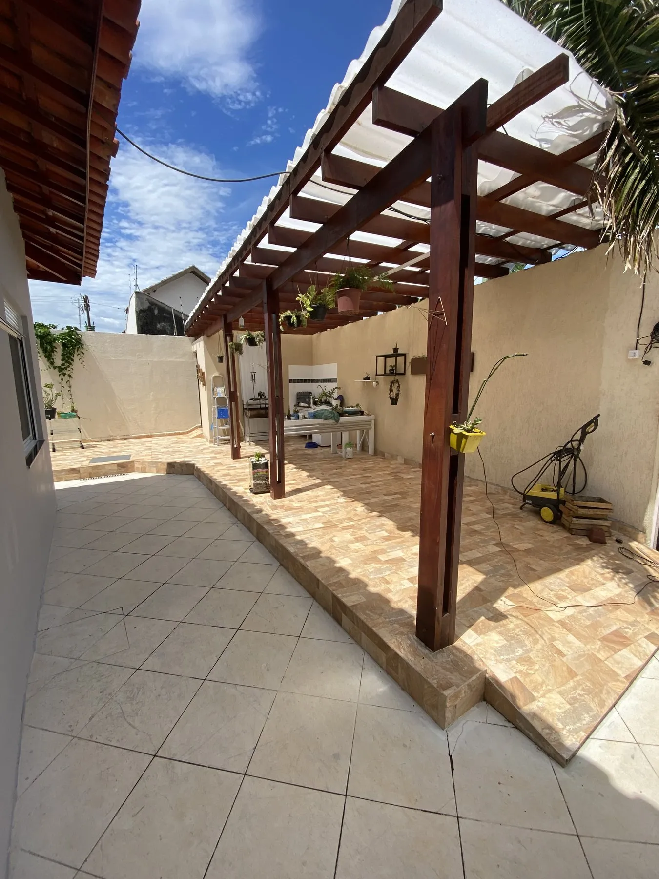 Quintal com piso cerâmico e pergolado de madeira antes da obra